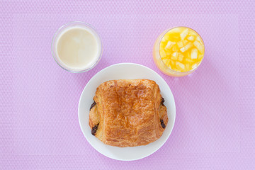croissants with chocolate filling on a white plate, orange juice, coffee. French pastries. side and top view, high key.