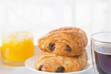 croissants with chocolate filling on a white plate, orange juice, coffee. French pastries. side and top view, high key.
