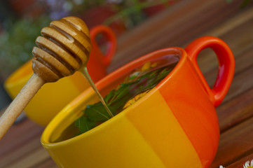 fresh honey flows into the herbal tea in an orange cup