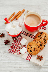Obraz na płótnie Canvas winter mood , cocoa with marshmallows in a red cup , cinnamon and cookies with chocolate on a wooden background