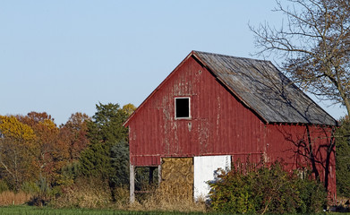 Old weathered and worn farm outbuilding in the country during the fall season with colorful foliage...