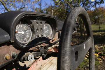 Steering wheel and rusty speedometer on vintage car dashboard