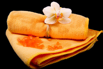 Obraz na płótnie Canvas flower yellow-orange orchids and orange towel on glossy black ba