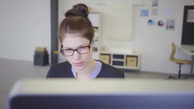 junge mitarbeiterin im b&uuml;ro sitzt am computer