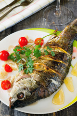 Baked fish with lemon on a dark wooden style