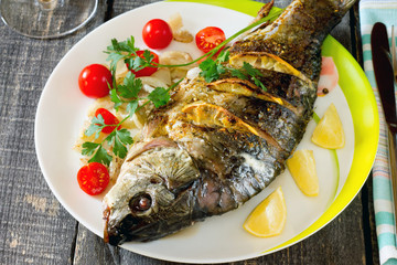 Baked fish with lemon on a dark wooden style