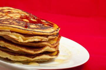 delicious pancakes with honey sauce on red background