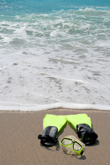 Conceptual snorkeling and swimming gear on beach sand