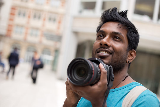 young indian man on holiday taking photos