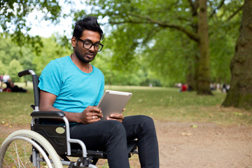 young indian man in a wheelchair using a tablet computer