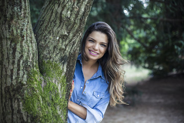 Naklejka premium Girl hides behind a tree trunk