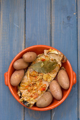 tuna with onion and potato in ceramic dish on blue background