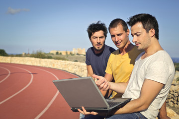 Three men watching something on a laptop