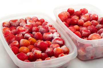 frozen strawberries in plastic box isolated on white
