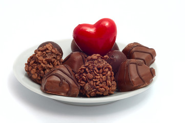 red heart and chocolates on white saucer separate on white