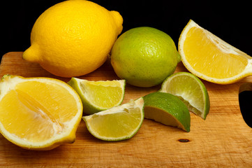 Fototapeta na wymiar slices of lemon and lime on the board separately on black