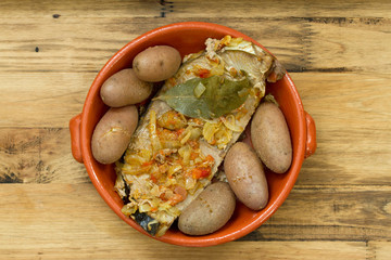 tuna with onion and potato in ceramic dish on brown background
