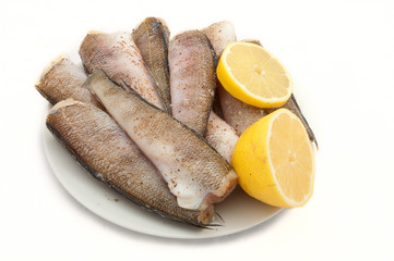 fish ready for cooking with spices ànd lemon on a plate on white