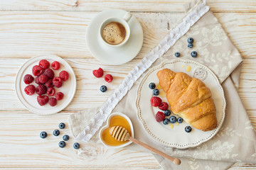 Breakfast with croissants, berries and honey on the table