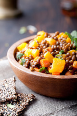 Lentil with carrot and pumpkin ragout in a wooden bowl.