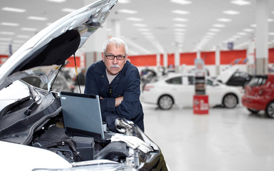 Smiling car mechanic in auto repair service. 