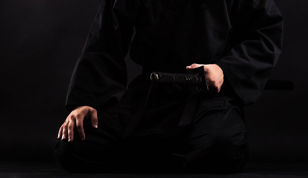 Close up of young martial arts fighter with katana siting in seiza position