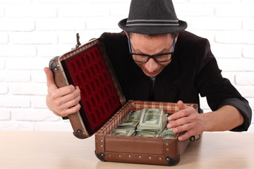 Emotional man in glasses holding bundles of money 