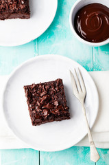 Chocolate brownie, cake, white plate on a turquoise wooden background