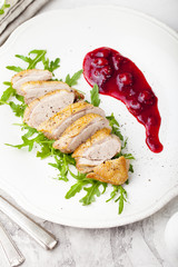 Duck breast meat with fresh salad, arugula and cherry sauce.