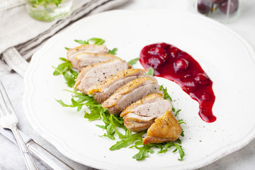 Duck breast meat with fresh salad, arugula and cherry sauce.