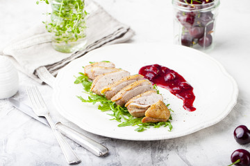 Duck breast meat with fresh salad, arugula and cherry sauce.