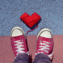 man in sneakers and heart-shaped coil of yarn on the asphalt