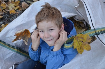 Kind hat Spaß mit Herbstlaub bei der Gartenarbeit