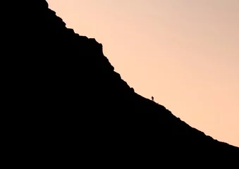 Fototapeten Lonely man climbing up to the mountain in sunset   © raz_sarbaste