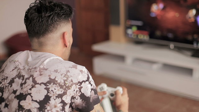 Guy Playing Videogame Whit Wireless Control Pad (back View)