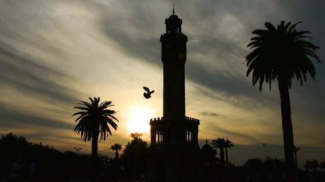 Historical clock tower  silhouette at sunset,  Izmir ( Smyrna ) - Turkey. Birds flying around. silhouette.