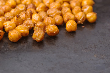 Chickpeas baked with spices closeup on black metal background with place for text