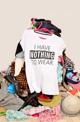 Big pile of clothes thrown on the ground with a t-shirt saying nothing to wear. Close up on a...