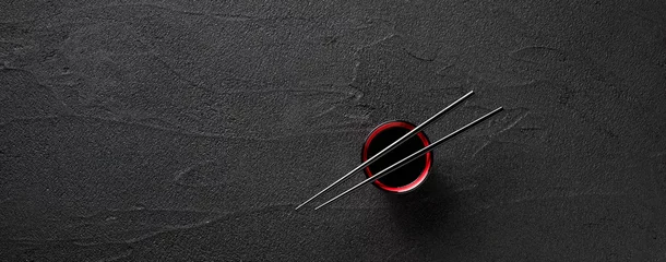 Tragetasche Essstäbchen und Schüssel mit Sojasauce auf schwarzem Steinhintergrund © nioloxs