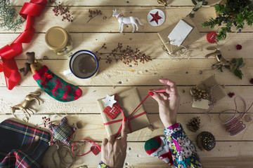 Woman decorating a Christmas present, surrounded by festive deco