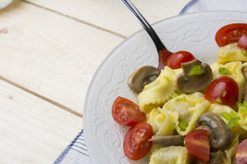 Homemade tortellini stuffed with mushrooms and spring onion and cherry tomatoes