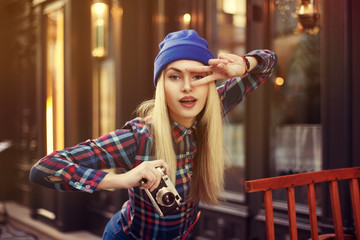 Portrait of beautiful young playful hipster woman with old retro camera. Model looking at camera....
