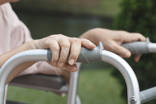 Elderly hands on a walker.