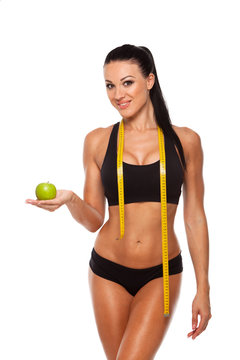 Sporty woman waist with measure tape and green apple isolated on white