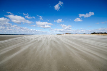 Blowing Sand across Empty Deserted Beach with Clear Sunny Blue Sky