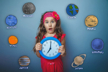 girl made a surprised face holding a clock planet of the solar s