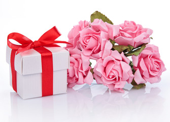 pink flowers and  gift box with red ribbon and bow on a white ba