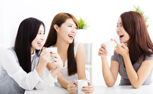 three happy young woman chatting in living room
