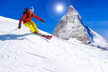 Skier skiing downhill against Matterhorn peak in Switzerland