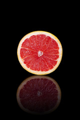 Half grapefruit on a black reflective background